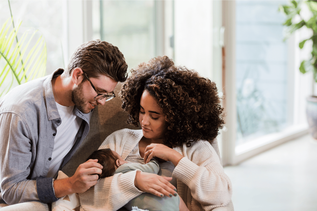 New mom and dad watch as baby breastfeeds
