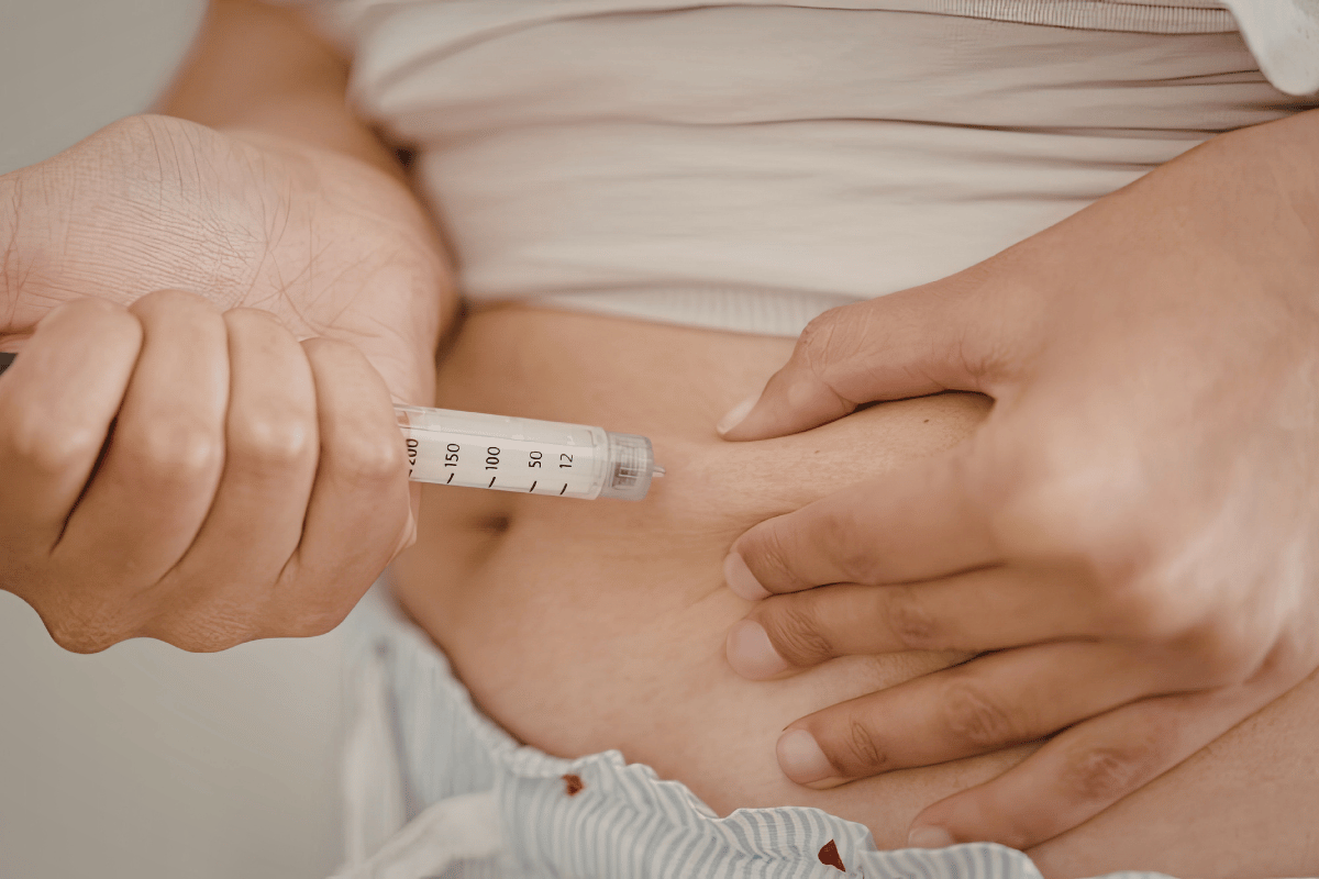 A person injecting insulin into their stomach