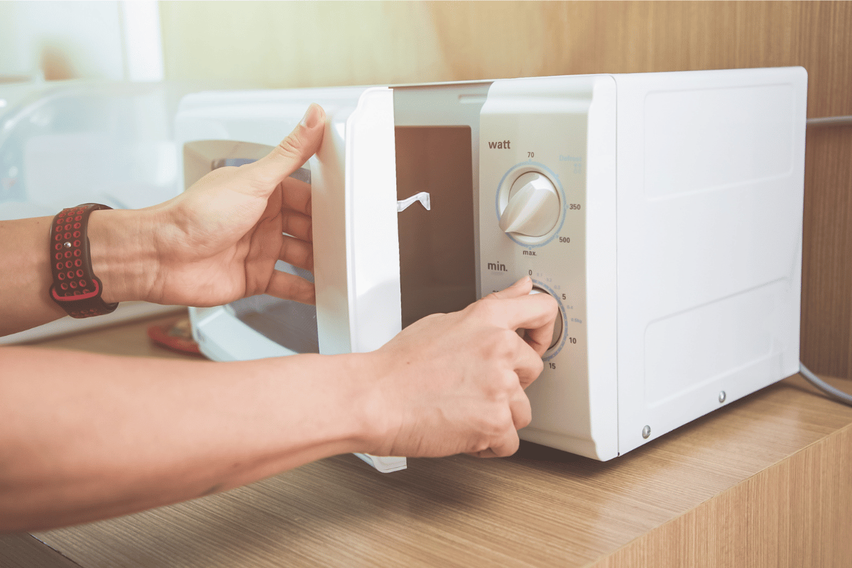 Woman's Hands Closing Microwave Oven Door And Preparing Food in microwave.