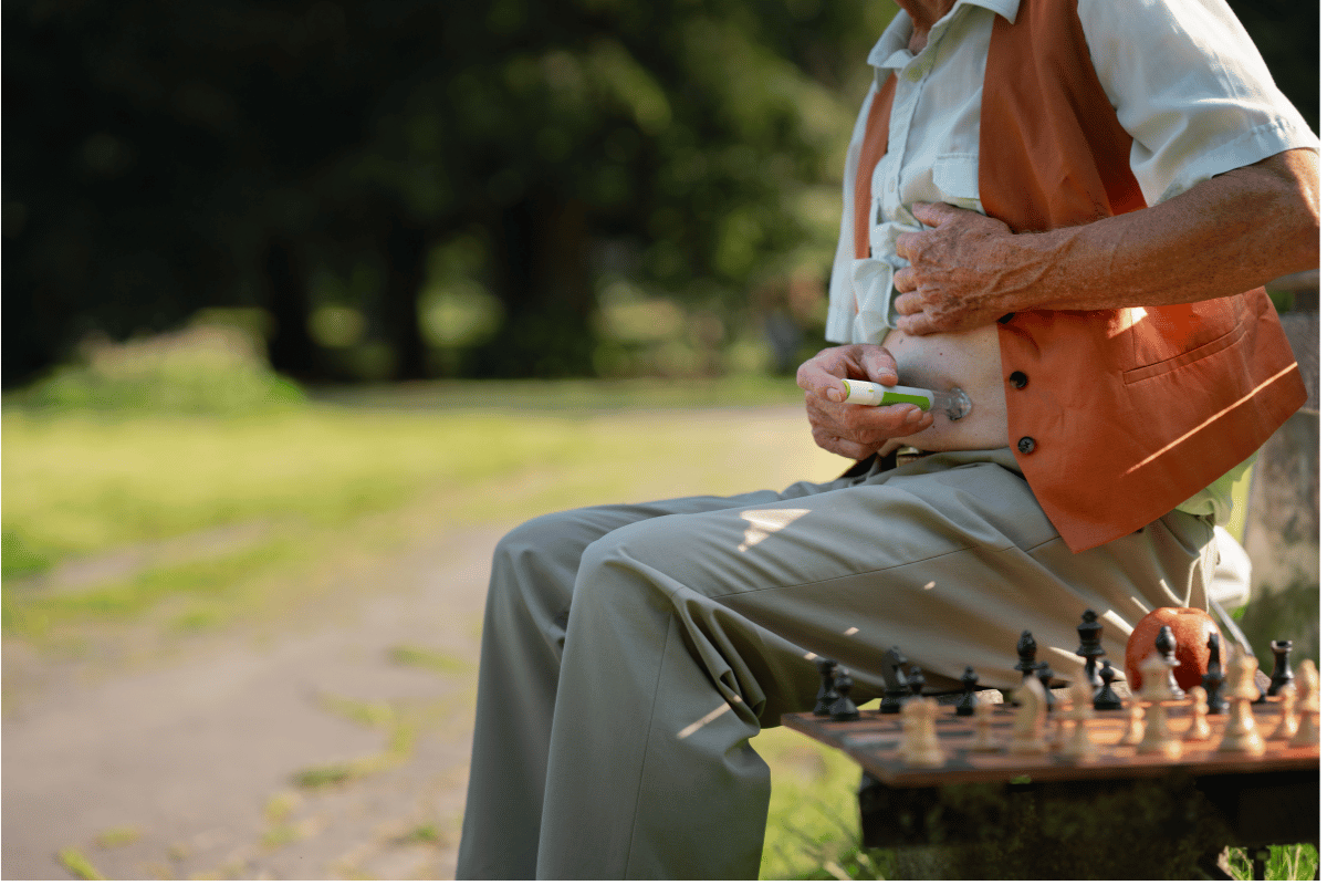 Elderly diabetic man injecting insulin in hisabdomen. Close up of senior man with type 1diabetes taking insuling with syringe needle incity park.